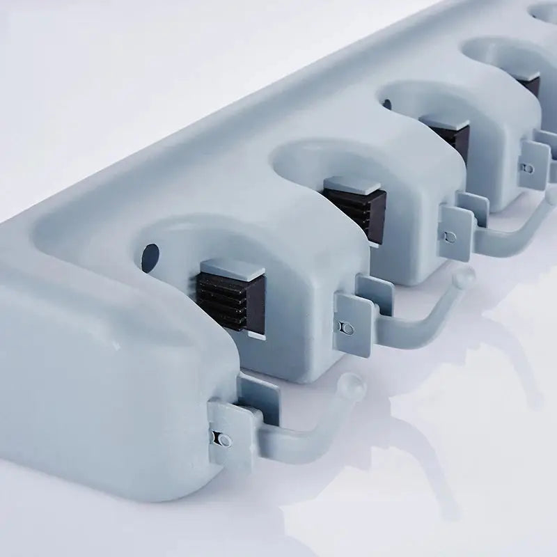 Close-up of a wall-mounted plastic bathroom shelf with a hook and rolling grip for holding mops and brooms. Multi-functional storage holder for washrooms and balconies.