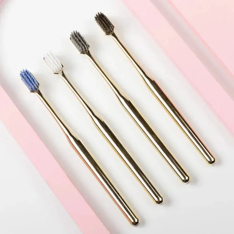 Top view of four luxury gold toothbrushes with soft bristles in various colors. Customizable wholesale toothbrushes for adults.